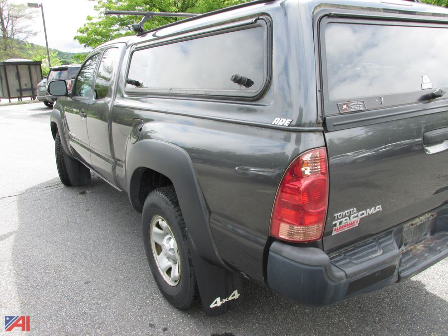 Toyota Tacoma pickup truck with cap, rear three-quarter view showing 4x4 badge and tailgate.