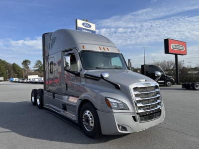 Freightliner Cascadia 126 truck in a dealership lot, silver exterior, side view showing cab and front grille.