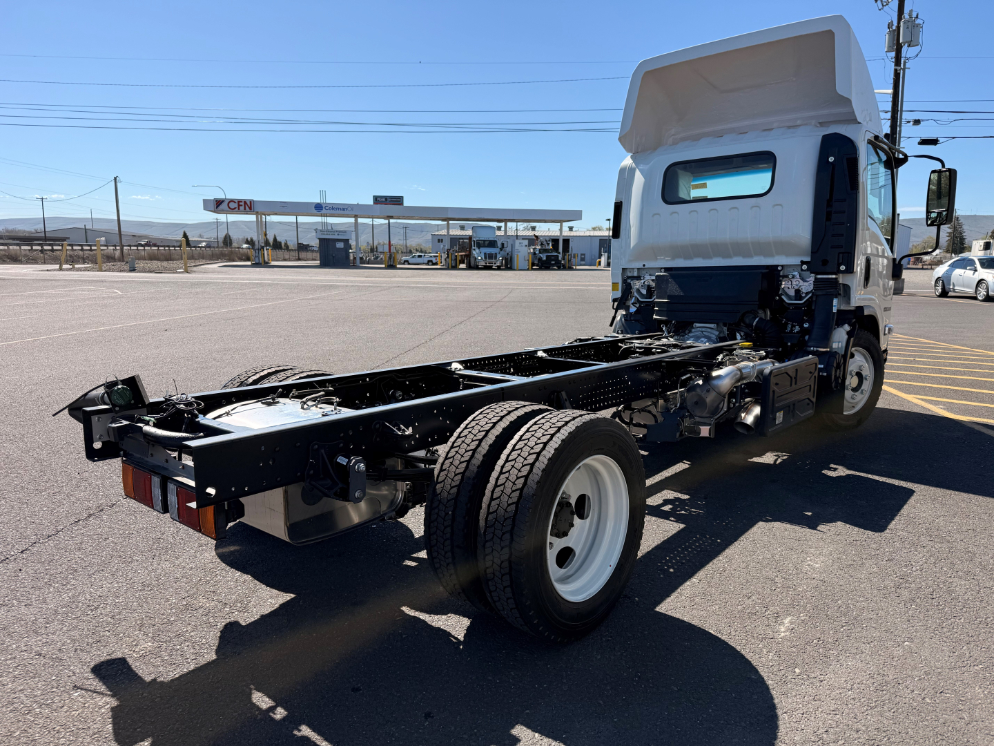 Isuzu NPRXD cab and chassis showing chassis frame and rear wheels with cab attached, side view with cab tilted forward.