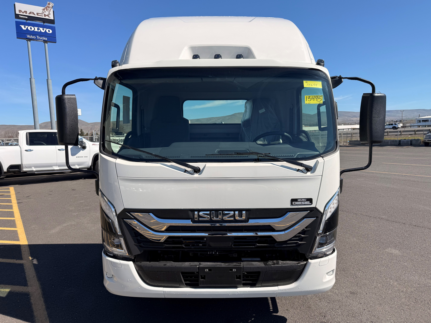 Isuzu NPRXD cab chassis front view showing large windshield, side mirrors, and Isuzu emblem on grille.