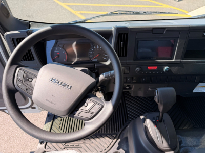 Isuzu NPRXD cabin interior showing steering wheel with Isuzu logo, dashboard, and gear selector in view