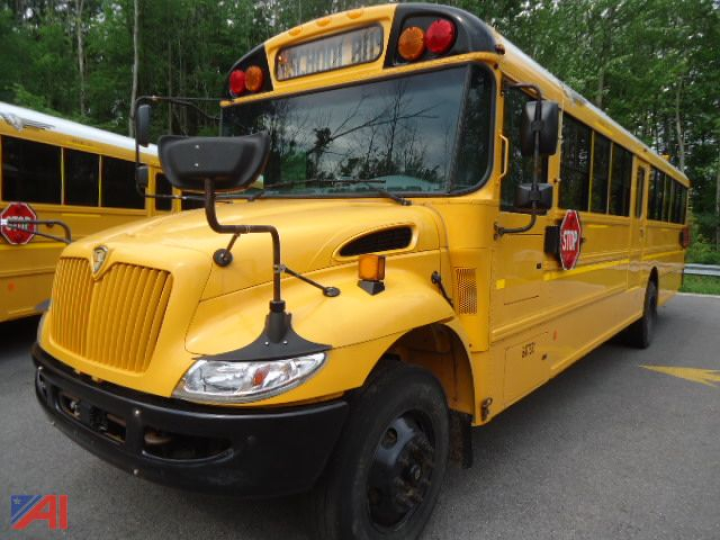 School bus front-left view, yellow IC Corporation CE Series bus with stop sign extended, bus number plate area, round headlights, black bumper, mirrors, and gray wheels.