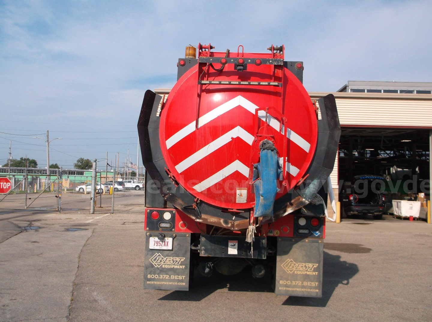 Back of Freightliner 114SD vacuum truck showing red tank with chevron markings and rear bumper lights.