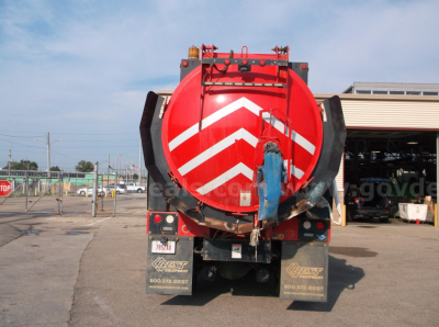Back of Freightliner 114SD vacuum truck showing red tank with chevron markings and rear bumper lights.