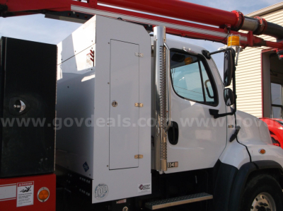 Freightliner 114SD vacuum truck side view showing cab and utility compartments with a red mechanical arm above.