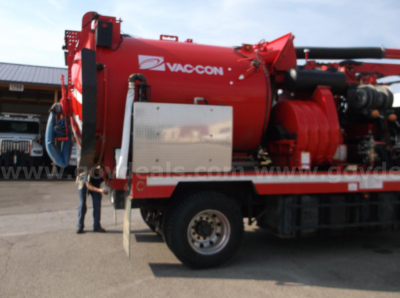 Vac-con vacuum truck on Freightliner chassis showing red vacuum tank with Vac-Con logo and control box mounted on side.
