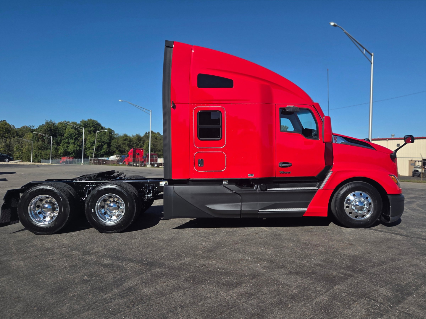 Kenworth T680 conventional sleeper truck side view showing red cab and triple rear axles with chrome wheels.