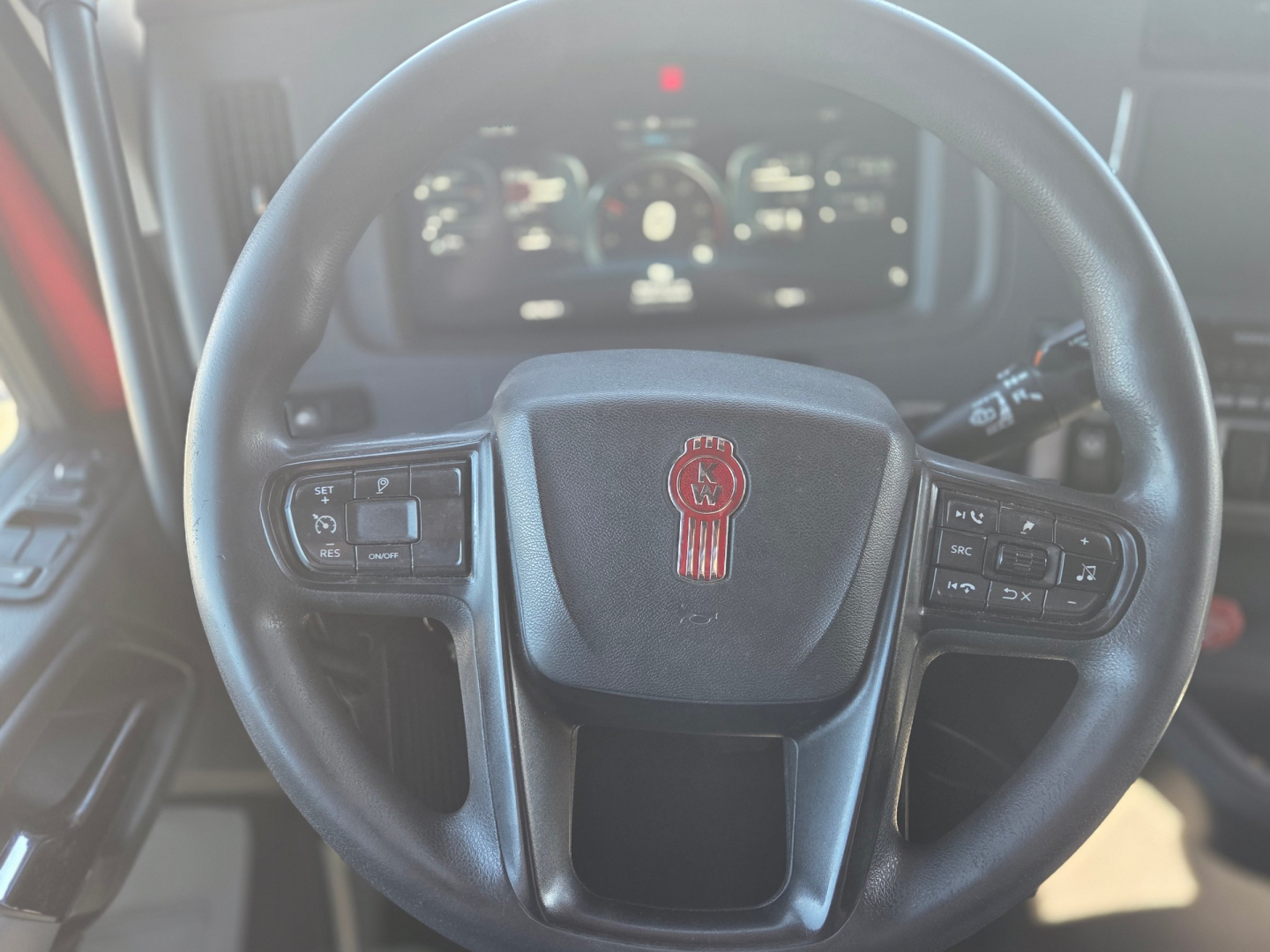 Kenworth T680 steering wheel with center logo and instrument cluster in background; view inside cab showing steering wheel controls