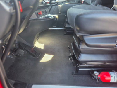 Kenworth T680 cab interior showing front passenger area with floor mat, seat base, red fire extinguisher, and cupholders.