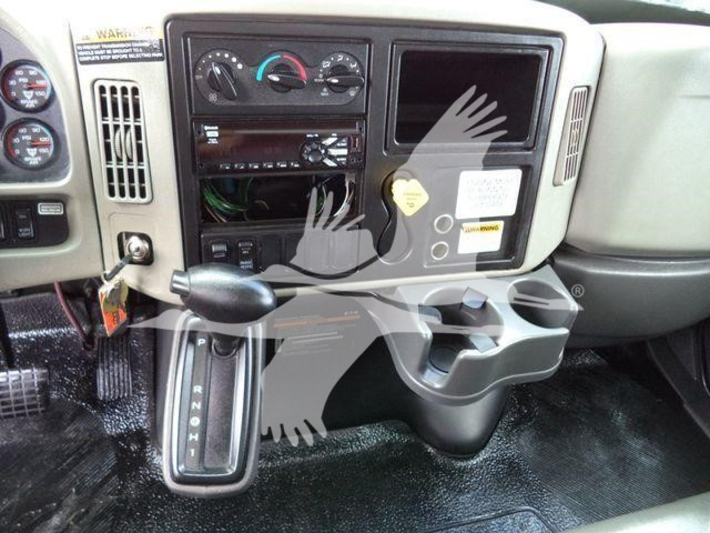 Dashboard of a 2019 International 4300 cab with manual gear shift and open panel showing radio area; several dials, switches, and an empty cassette slot.