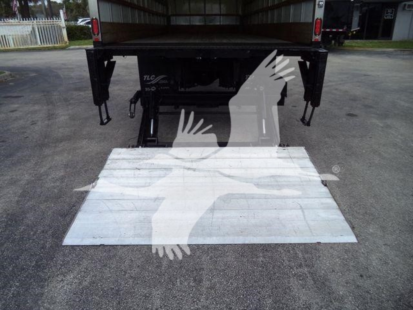 Truck rear with loading ramp extended showing metal platform and frame under a box truck bed.