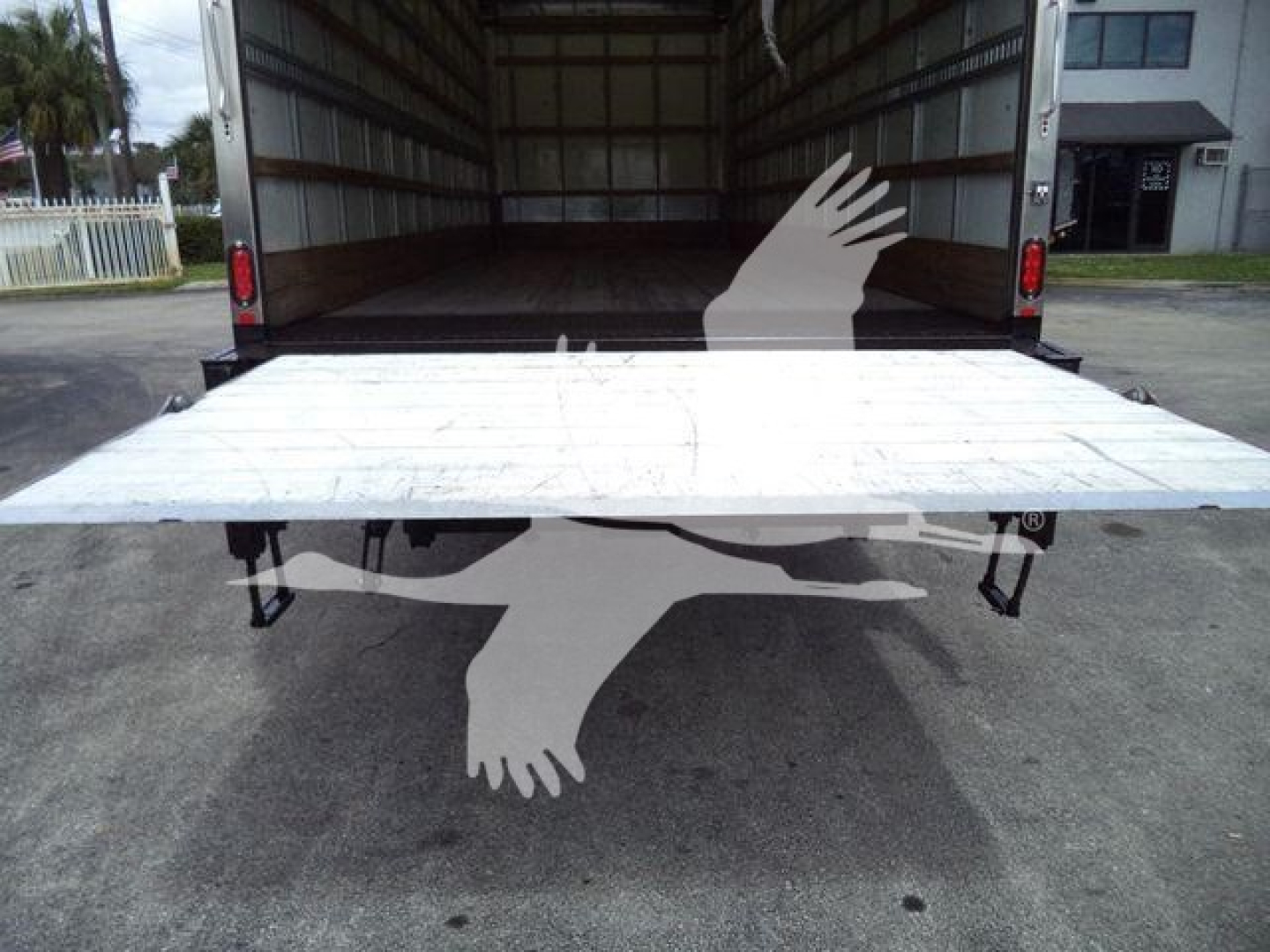 Truck cargo area with ramps deployed at rear, interior of cargo box, white platform extended outward.