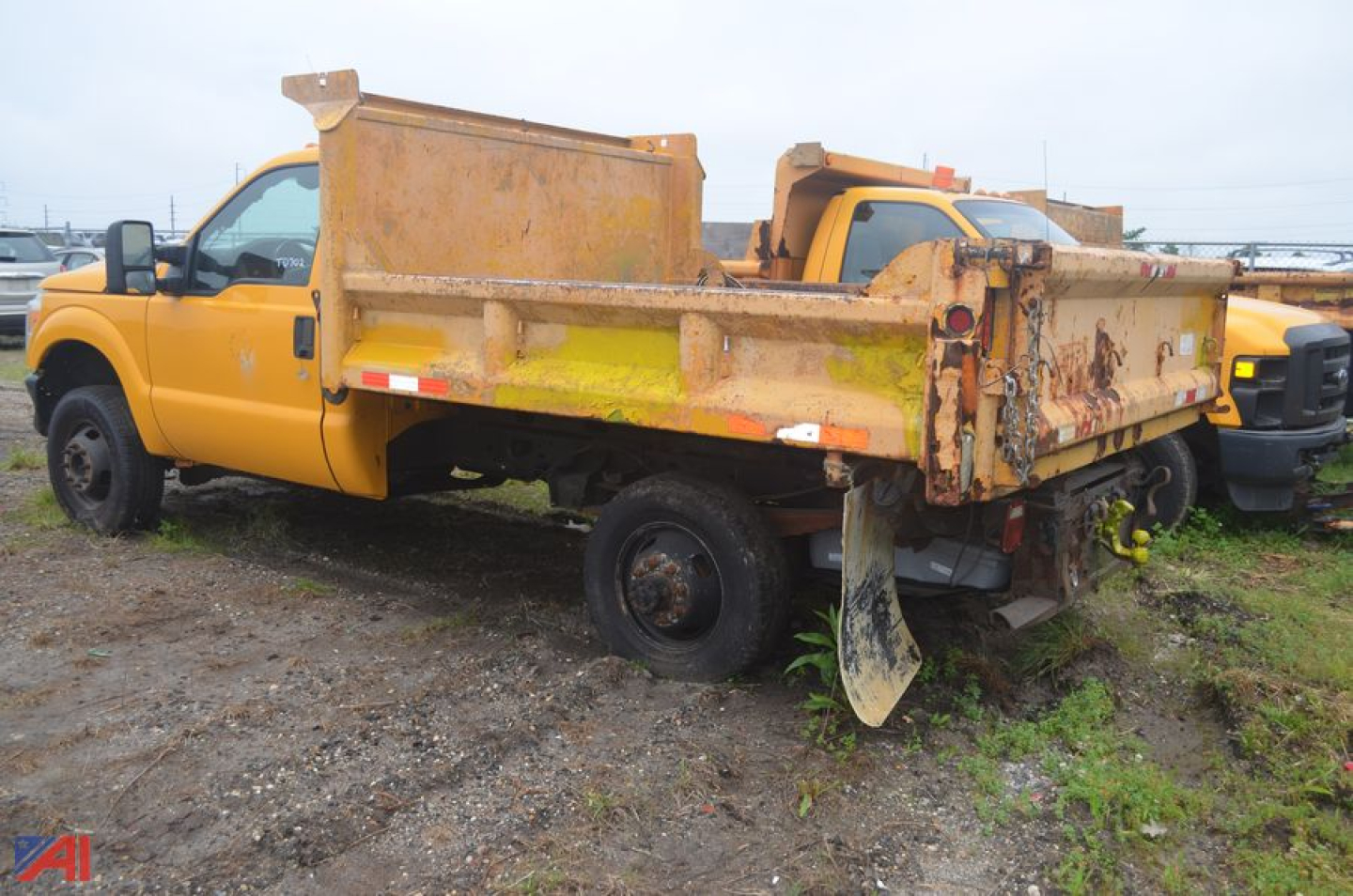 Dump truck body and bed of a yellow 2011 Ford F350 Super Duty dump truck, side view showing dump bed with dirt and wear.