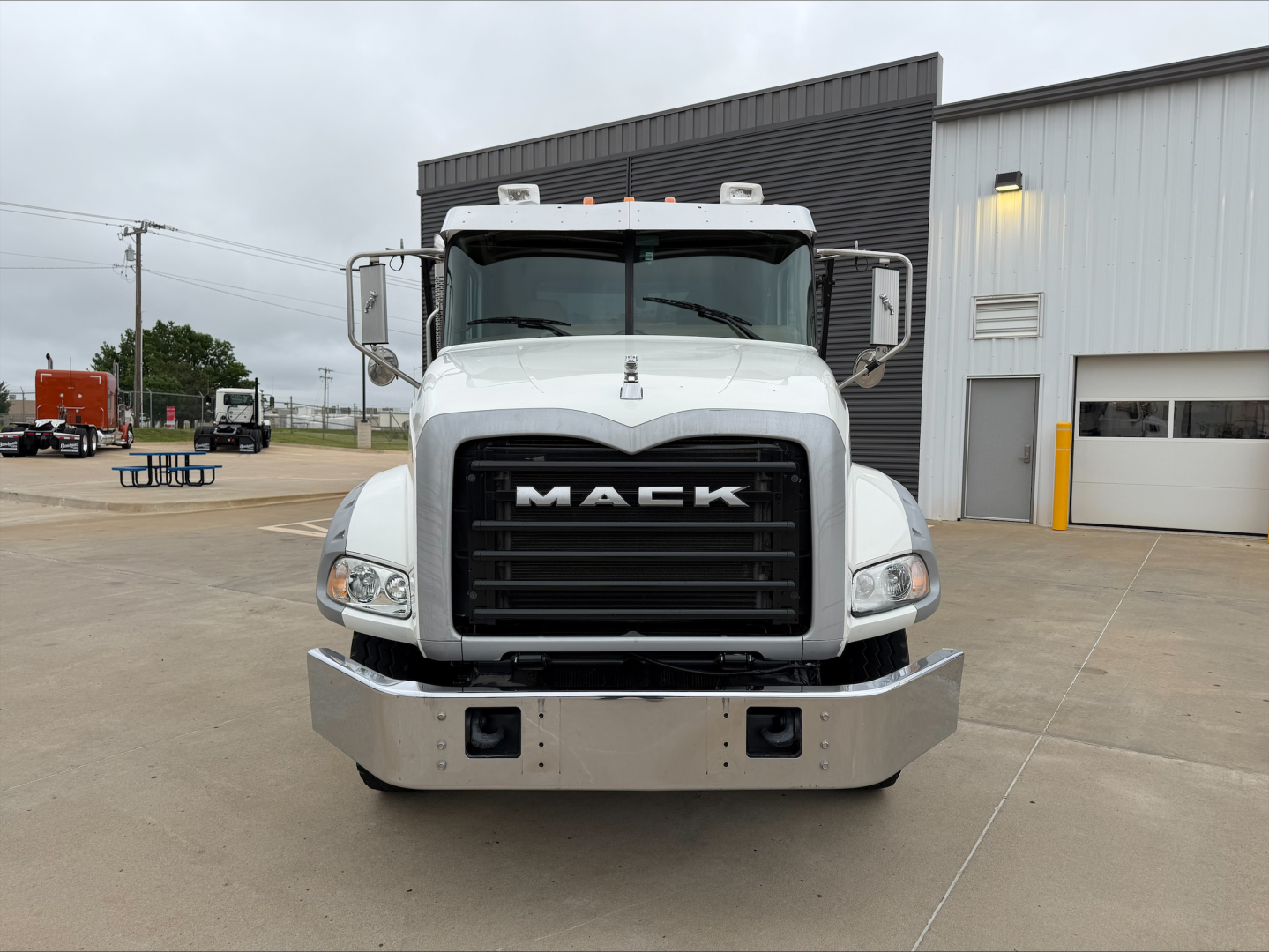 Front view of a white 2016 Mack GU533 roll-off truck showing chrome bumper, black grille with MACK logo, and large side mirrors.