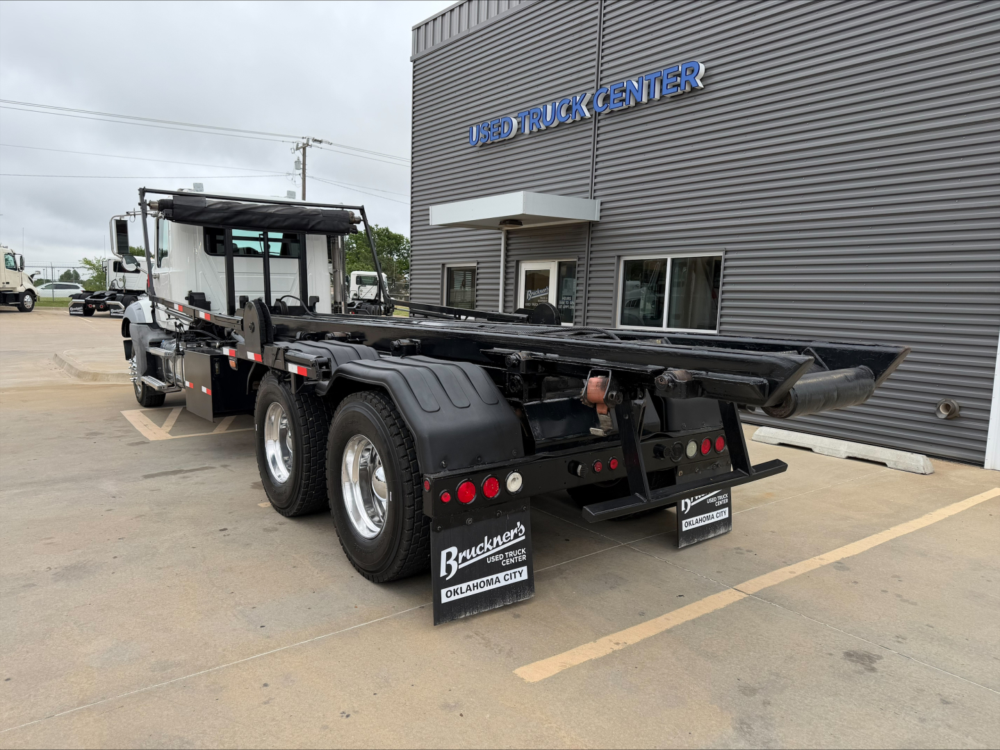 Mack GU533 rollback truck trailer rear view showing dual rear axles, black chassis, mud flaps, and company signage.