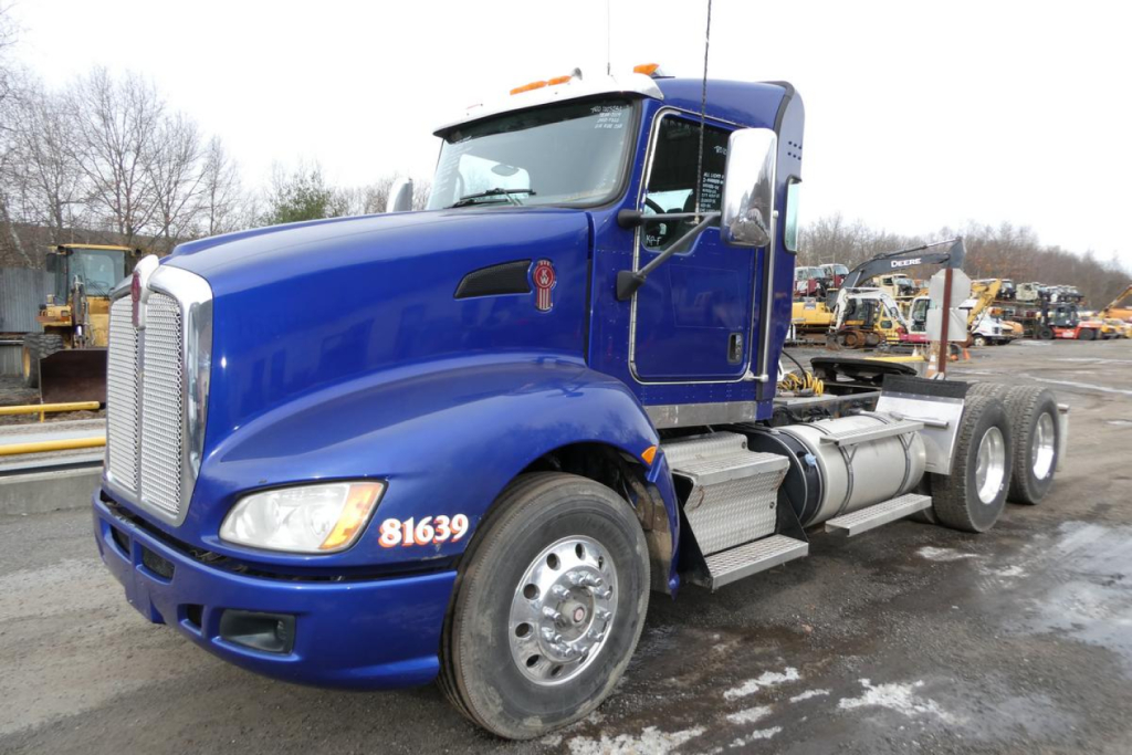 Kenworth T660 daycab tractor in blue, side view showing front grille, cab, and dual rear axles. Visible numbers: 81639 on front fender; background equipment yard.