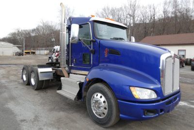 Kenworth T660 conventional daycab truck in blue showing cab, dual rear axles, chrome exhaust stack, and side steps.
