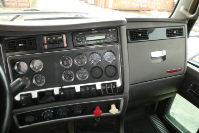Kenworth truck dash panel showing multiple gauges, switches, and vents; standard cab interior with gray and black plastics.