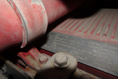 Kenworth T660 engine bay with belt and label showing tire size and numbers, close-up of metal plate with small printed text.
