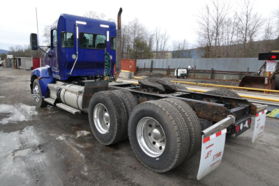 Blue Kenworth T660 tractor with rear chassis and dual rear axles, front cab side mirrors, fuel tanks, and mud flaps. Text visible on mud flap and chassis includes reflective stripes and highway markings.