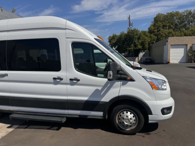Ford Transit 350 HD XLT passenger van side profile showing front wheel and running board with high roof, white exterior, and side window.