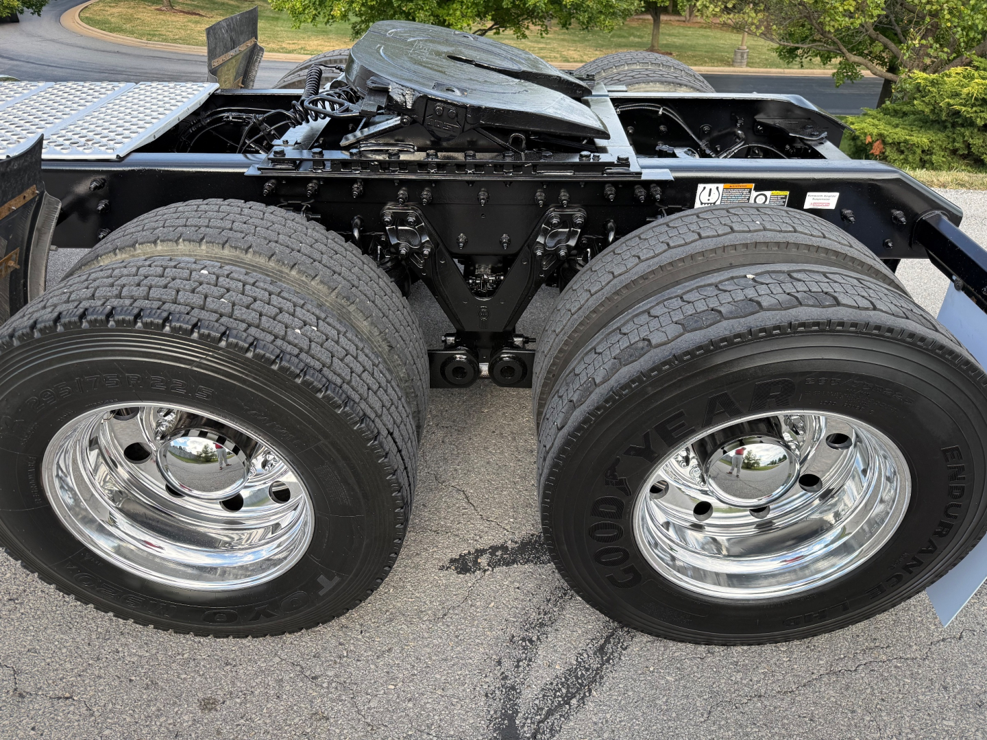 Kenworth T880S wheel pair showing dual rear axles and chrome rims, with chassis frame and fifth wheel visible.
