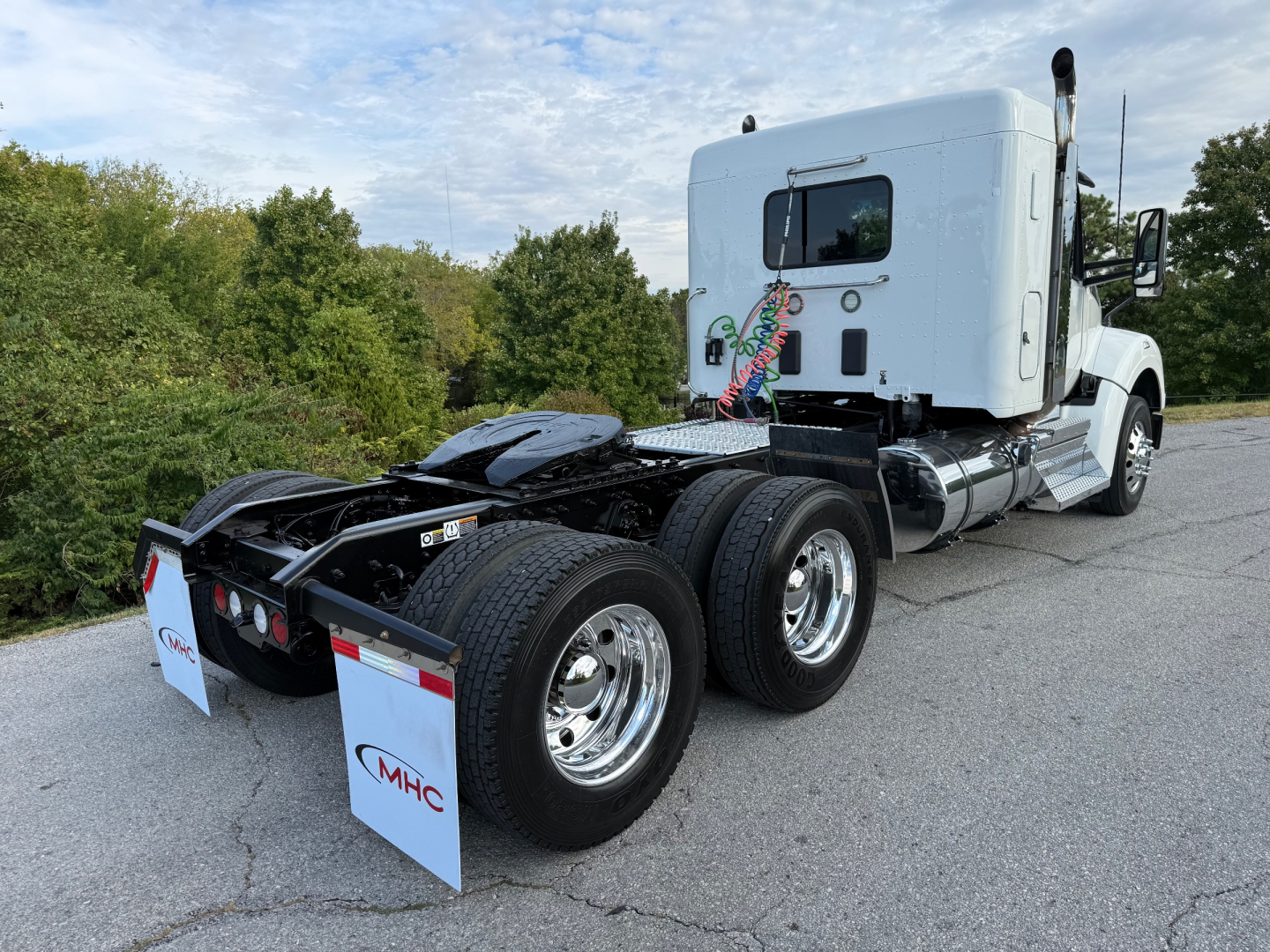 Kenworth T880S tractor cab seen from rear-left, showing fifth-wheel area and dual rear axles with chrome wheels, white sleeper cab, and MHC trailer mud flaps.