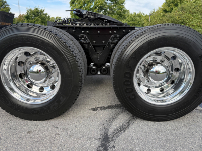 Kenworth T880S chassis with dual rear wheels showing chrome rims and Goodyear tires; suspension and drivetrain components visible between wheels.