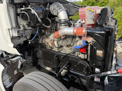 Kenworth T880S engine bay showing turbo intake pipe, hoses, radiator, coolant reservoir, and engine block.
