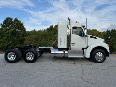 Kenworth T880S tractor cab side view showing chrome fuel tanks, dual rear axles, and aerodynamic hood. VIN and stock not visible in image.