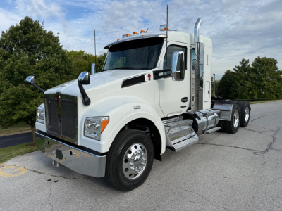 Kenworth T880S conventional sleeper truck in white, front-left view showing cab, polished chrome bumper, hood emblem, dual exhaust, and tandem rear wheels.