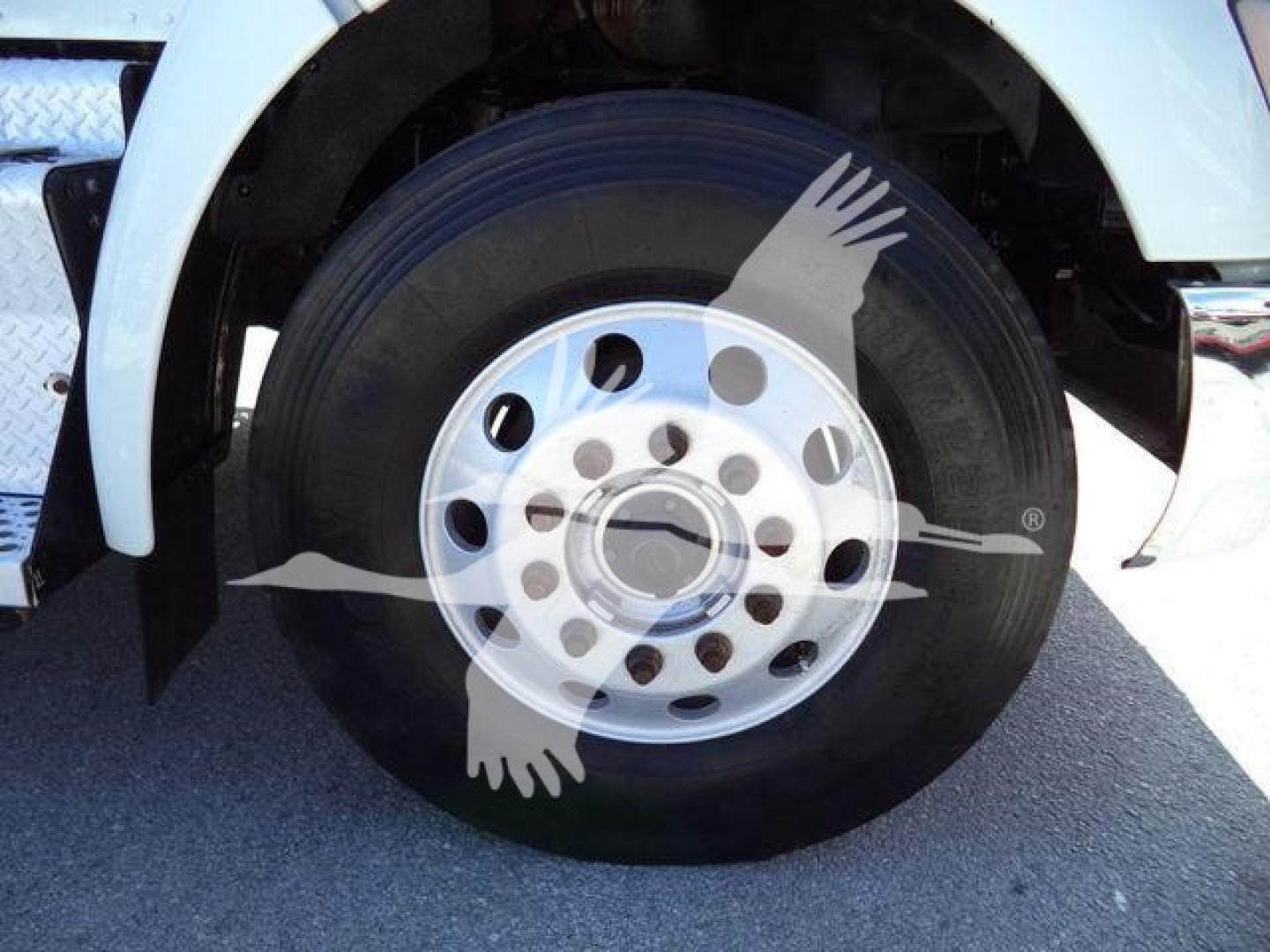 Front wheel and tire of a Kenworth T270 showing chrome hub and black tire, partial white fender and wheel well.