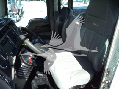 Truck interior showing driver seat and dashboard of a Kenworth T270 cab. Visible text includes a steering wheel, manual gear shifter, and grey cloth seats. No additional legible labels or serials in view.