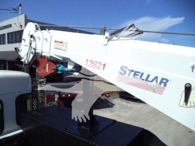 Telescoping crane arm with 'STELLAR' logo and red serial number '12621' on white boom, blue sky background; portion of vehicle cab and hydraulic components visible.