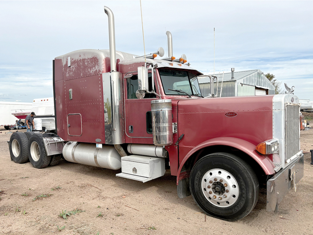 Peterbilt 379 UltraCab conventional sleeper truck with extended hood, maroon color, chrome exhaust stacks, daytime running lights, dual rear wheels.