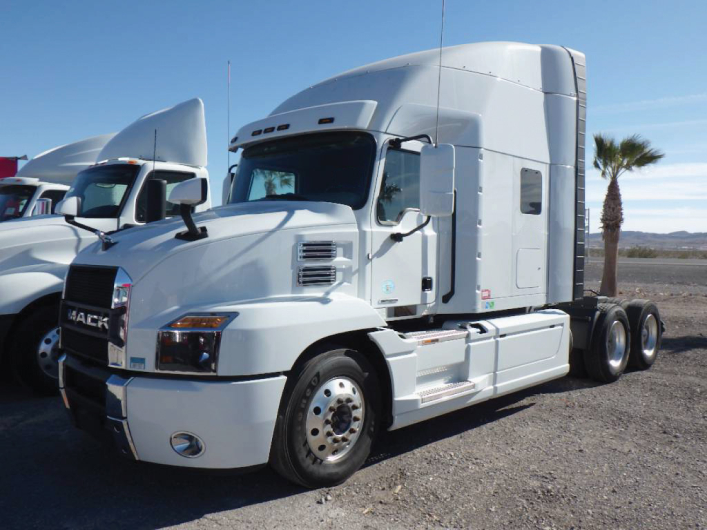 Mack Anthem semi-truck in a lot, front quarter view showing sleeper cab, chrome wheel, side fuel tank, and dual rear axles.