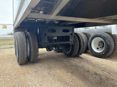 Hopper trailer undercarriage showing dual axle suspension and aluminum frame with tires and landing gear in view.