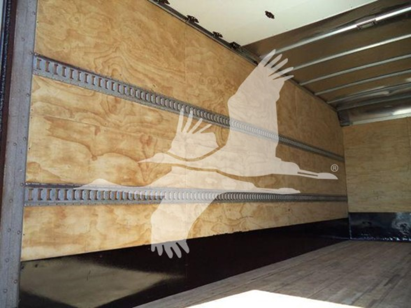 Isuzu NPR box truck interior showing wooden cargo walls and metal E-track rails along the sides.