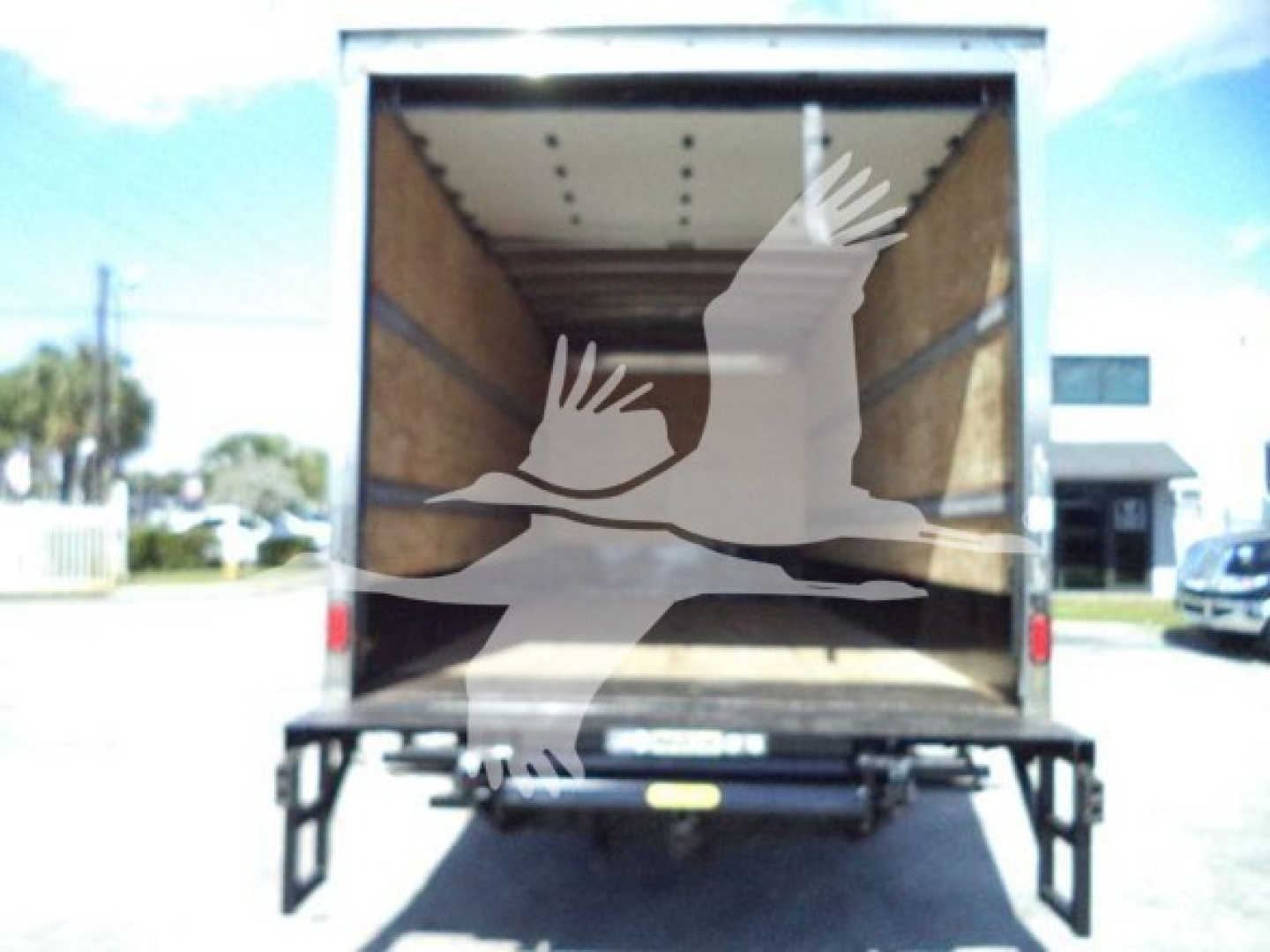 Isuzu NPR box truck rear view showing empty cargo area with wooden walls and open rear doors.