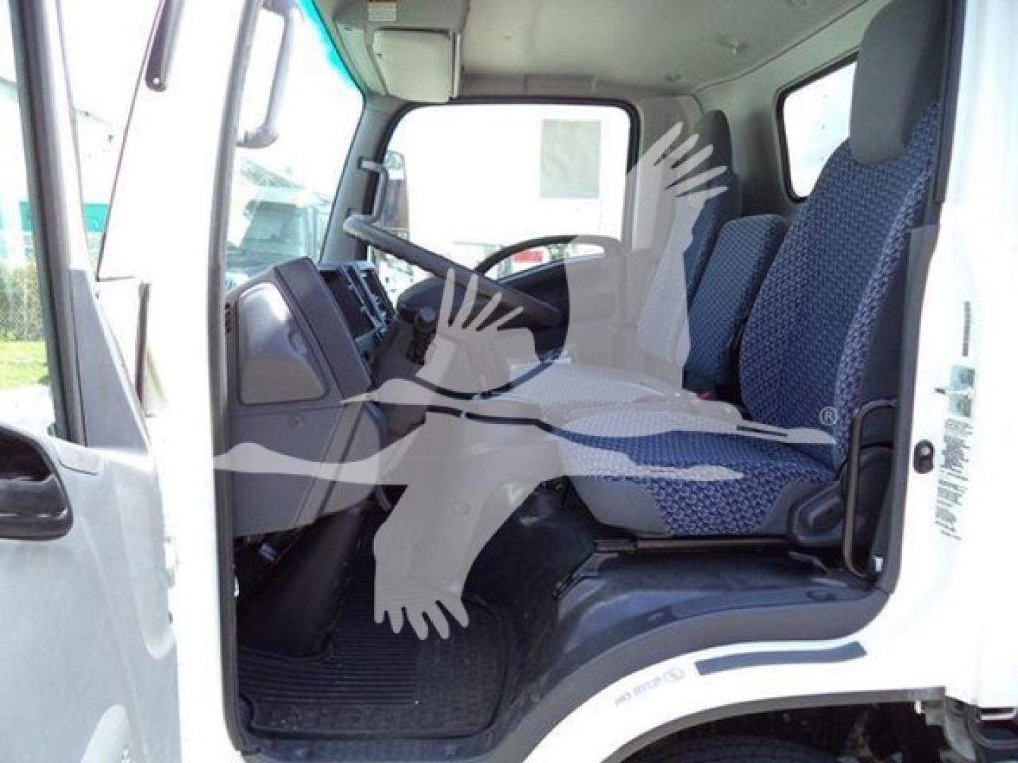 Isuzu NPR cab interior viewed from open driver door showing steering wheel, dashboard, and two front seats.