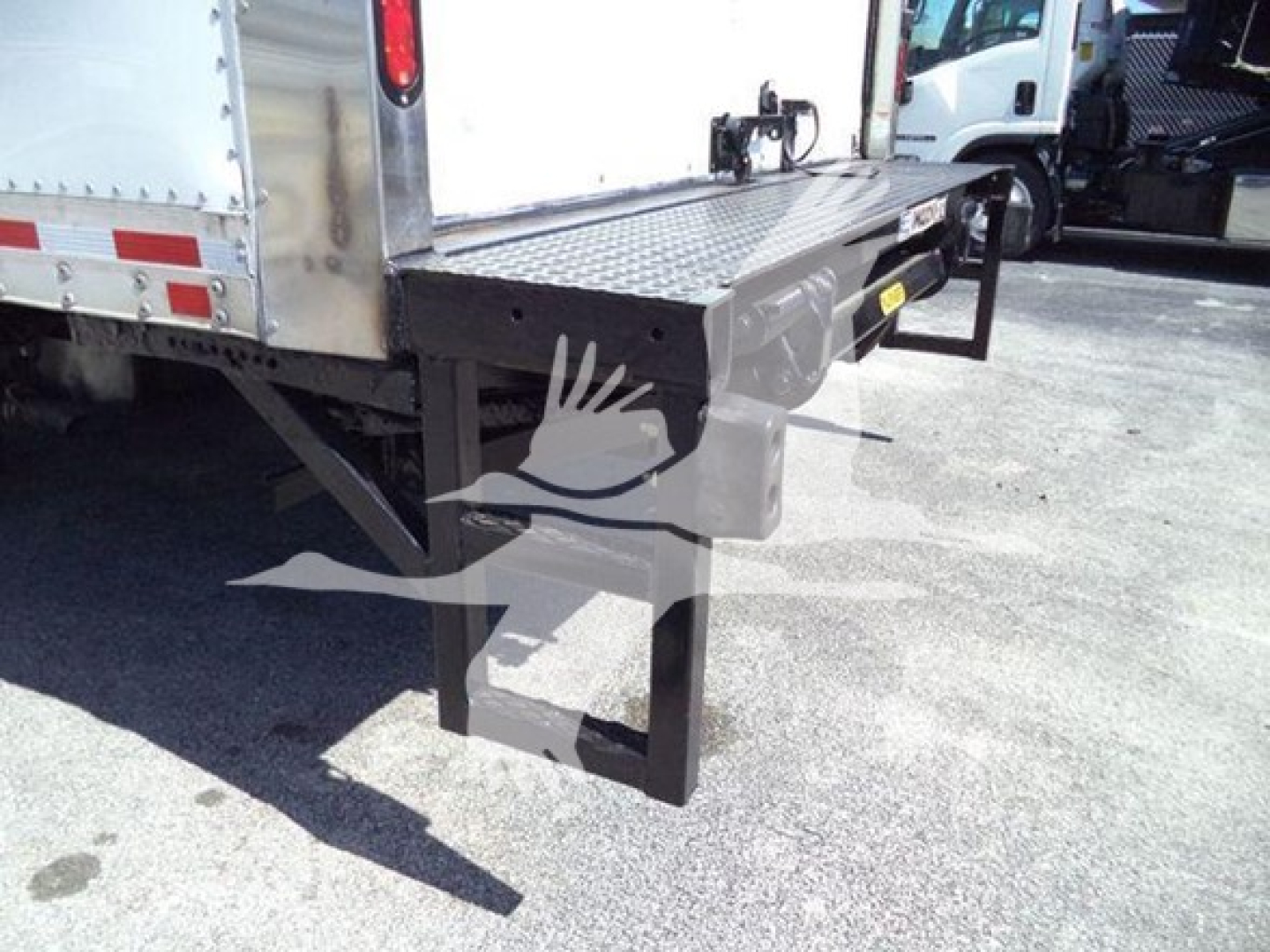 Isuzu NPR box truck rear bumper and step with metal platform wheel-lift visible.