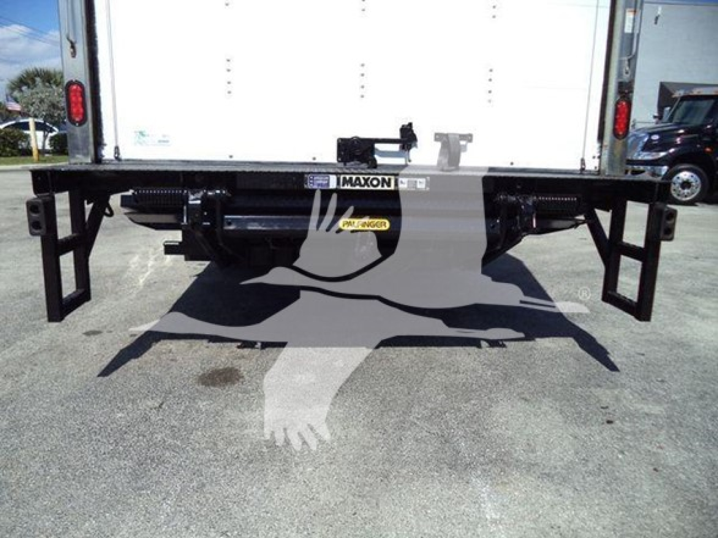 Isuzu NPR rear view showing Maxon bumper and under-rail pallet fork apparatus, black steel frame with support brackets.