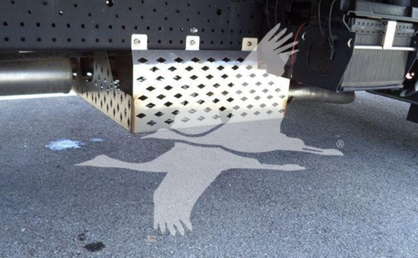 Underbody view of Isuzu NPR truck showing exhaust, metal skid plate, and wiring with perforated guard.