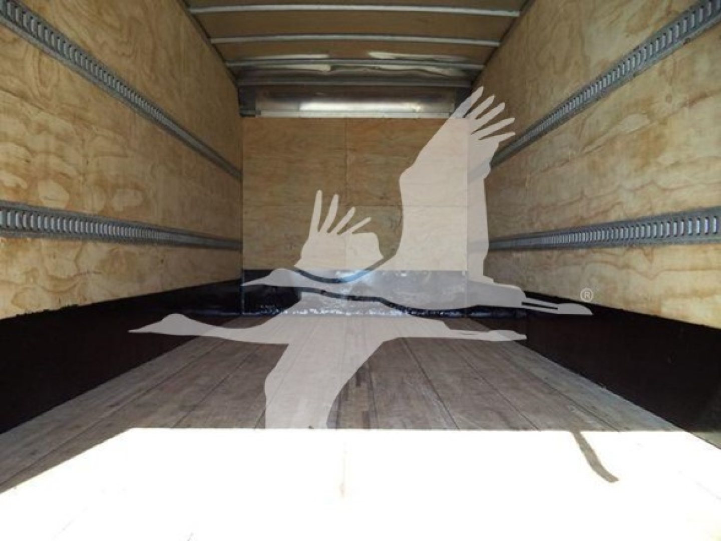 Trailer interior with wooden walls and metal arch rails; silhouette watermark of hands and a dove on the floor.