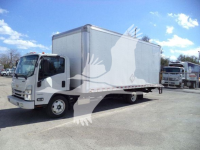 Box truck chassis with a large white cargo box, Isuzu NPR type, front cab visible, parked in lot.