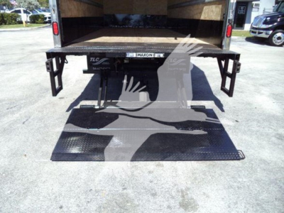 Isuzu NPR box truck rear view showing wheelchair lift/platform in lowered position with open cargo area and ramp.