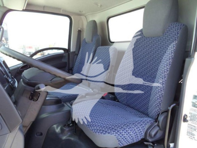 Isuzu NPR truck interior showing front seats and steering wheel from driver side, blue patterned seat covers, dashboard and door panels visible.