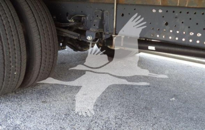 Underbody view of Isuzu NPR truck showing frame and dual rear wheels; no legible labels or fluid reservoirs visible.