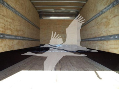 Trailer interior with wooden walls and metal arch rails; silhouette watermark of hands and a dove on the floor.