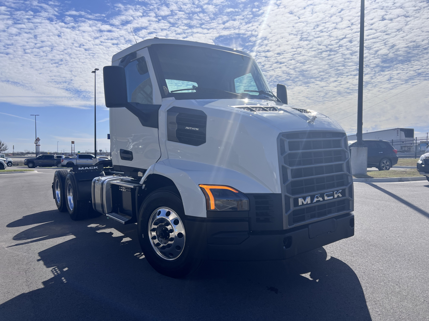Truck cab front view of a white 2027 Mack AN64T with large grille and side mirrors.